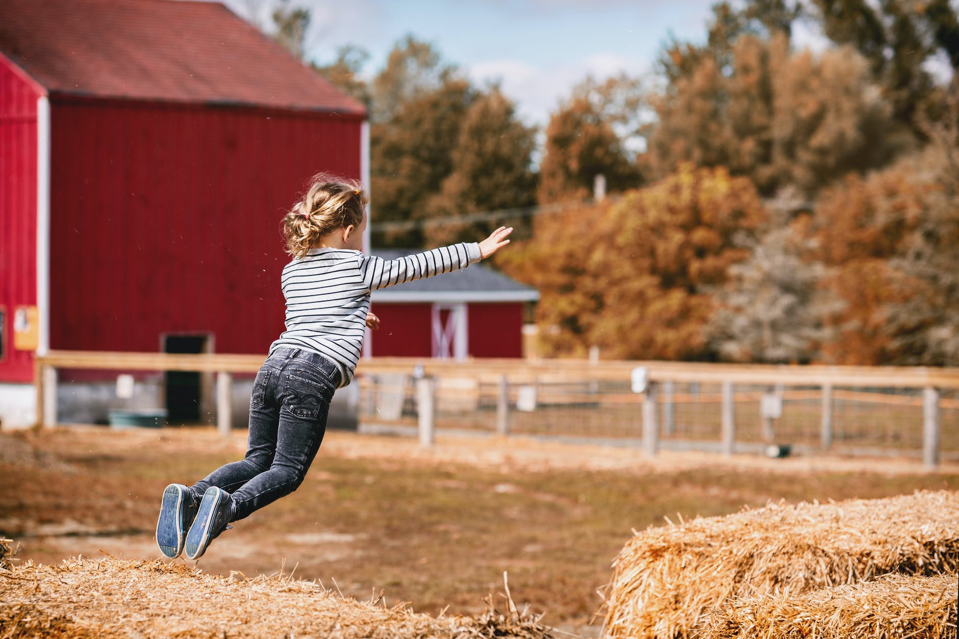 girl wearing white and black striped long sleeved shirt jumping outdoor